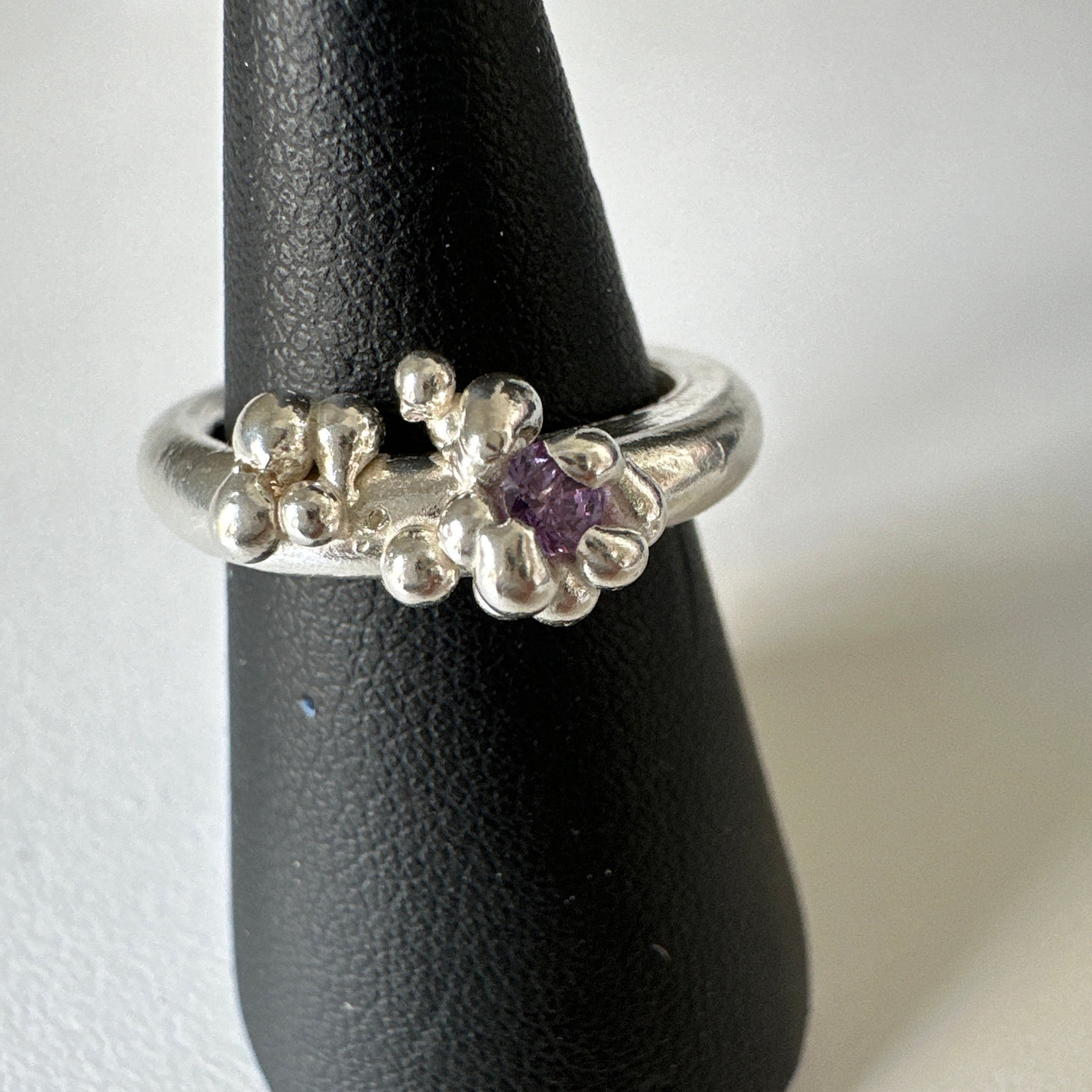 Lost wax silver ring with delicate granulations around a violet cubic zirconia stone