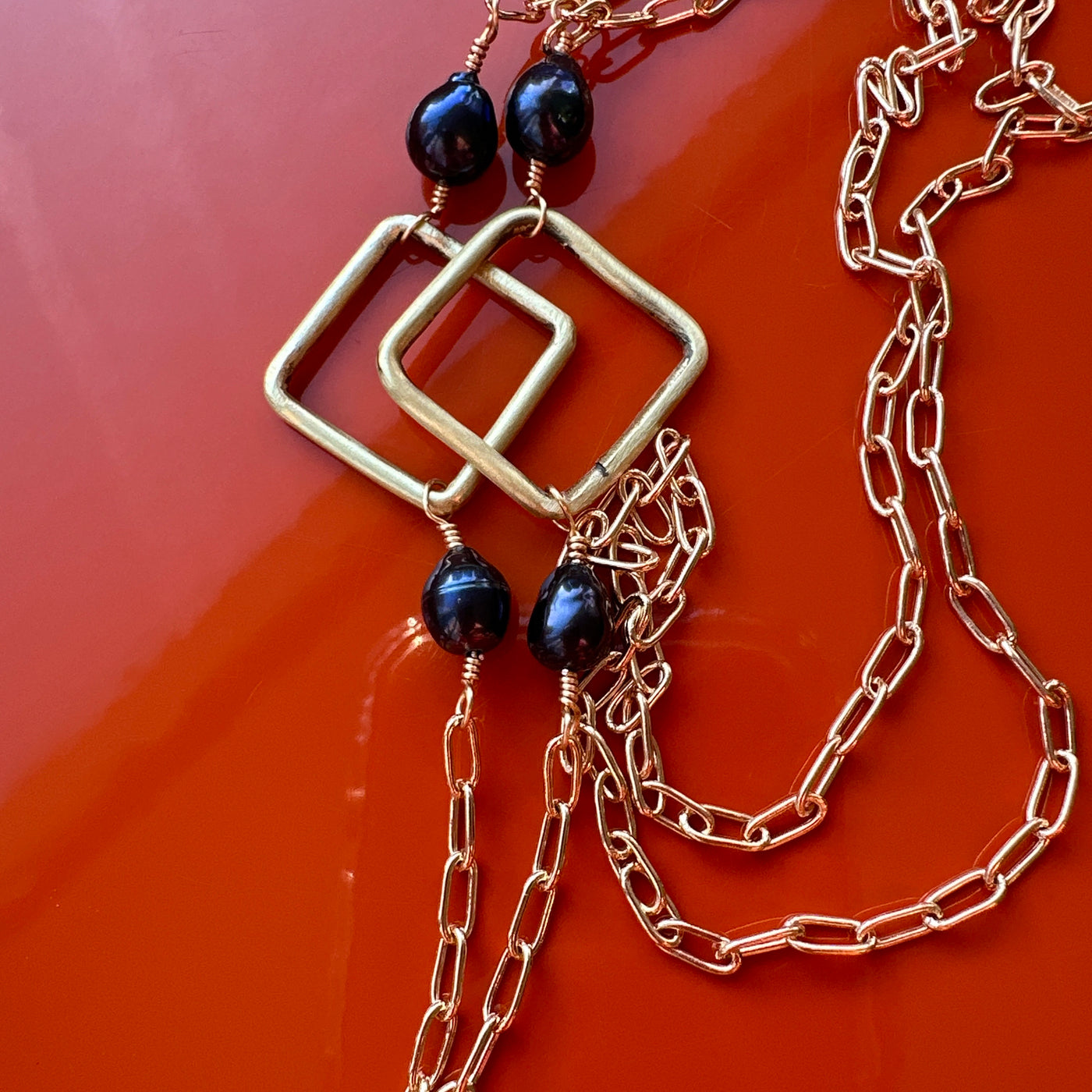 Necklace featuring brass rectangle and squares with black pearls