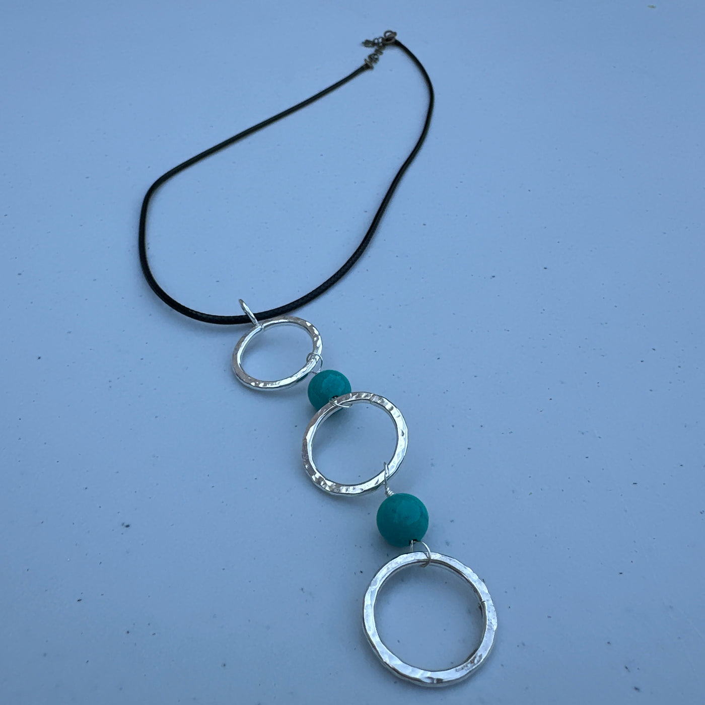 Three circle rings and turquoise pendant on simple lace