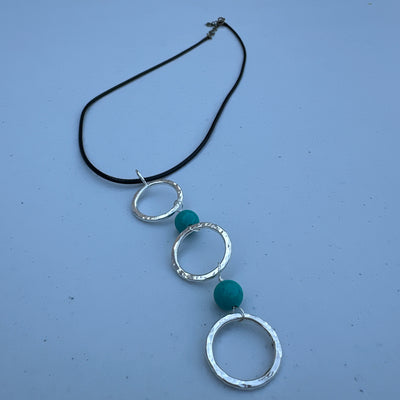 Three circle rings and turquoise pendant on simple lace