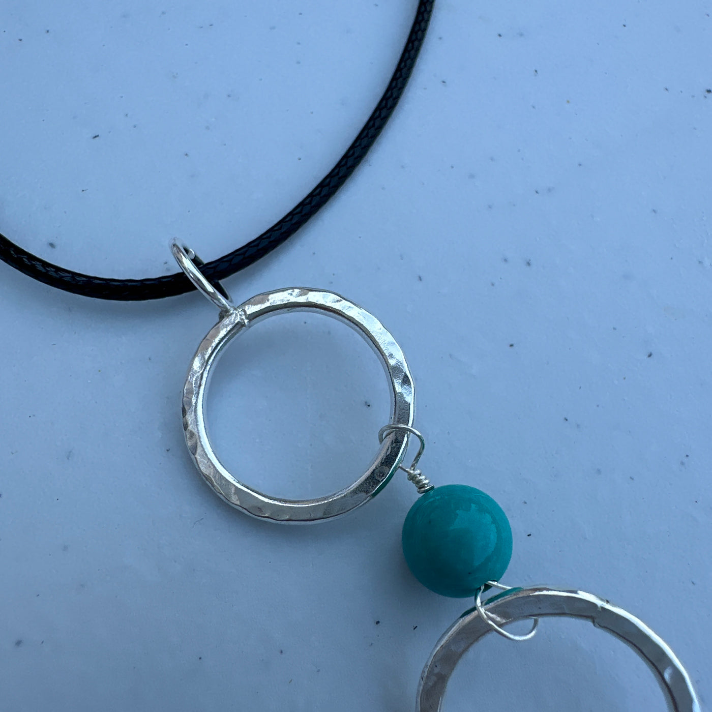 Three circle rings and turquoise pendant on simple lace