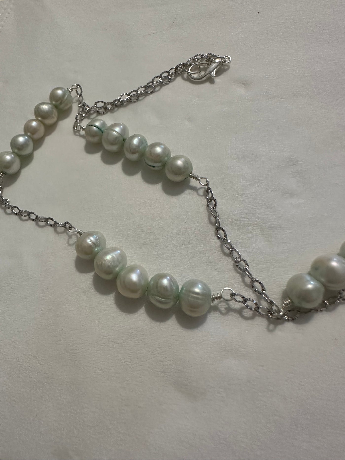 Necklace featuring freshwater pearls -light turquoise- on rhodium plated brass chain