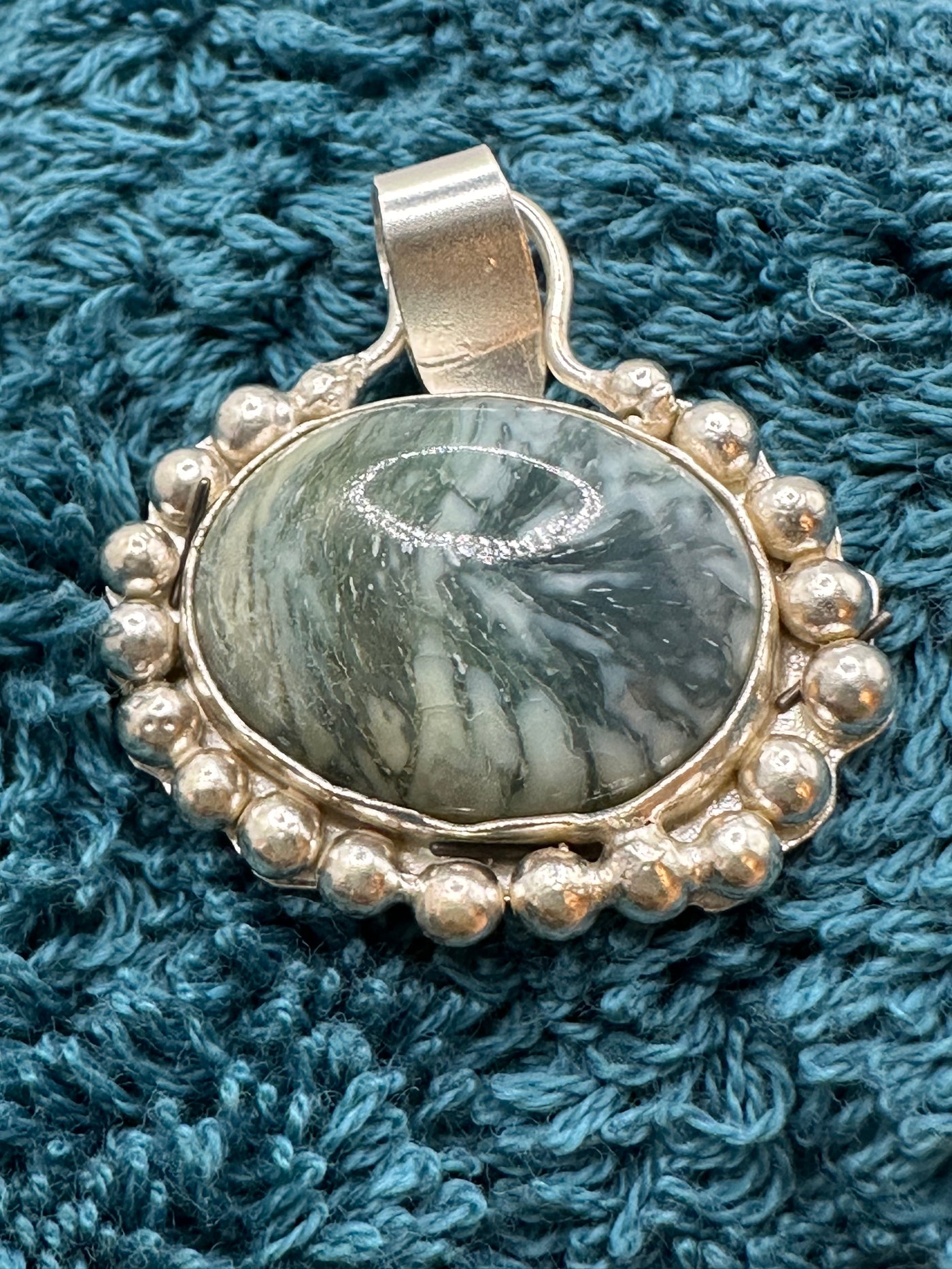 Green marbled stone pendant incapsulated in silver granulations