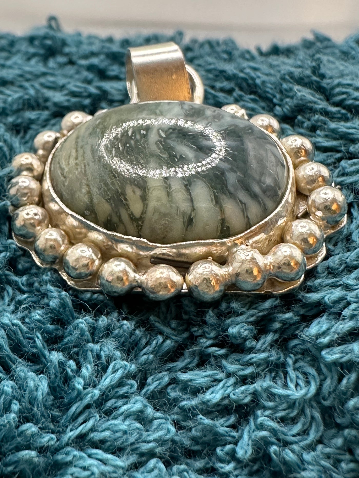 Green marbled stone pendant incapsulated in silver granulations