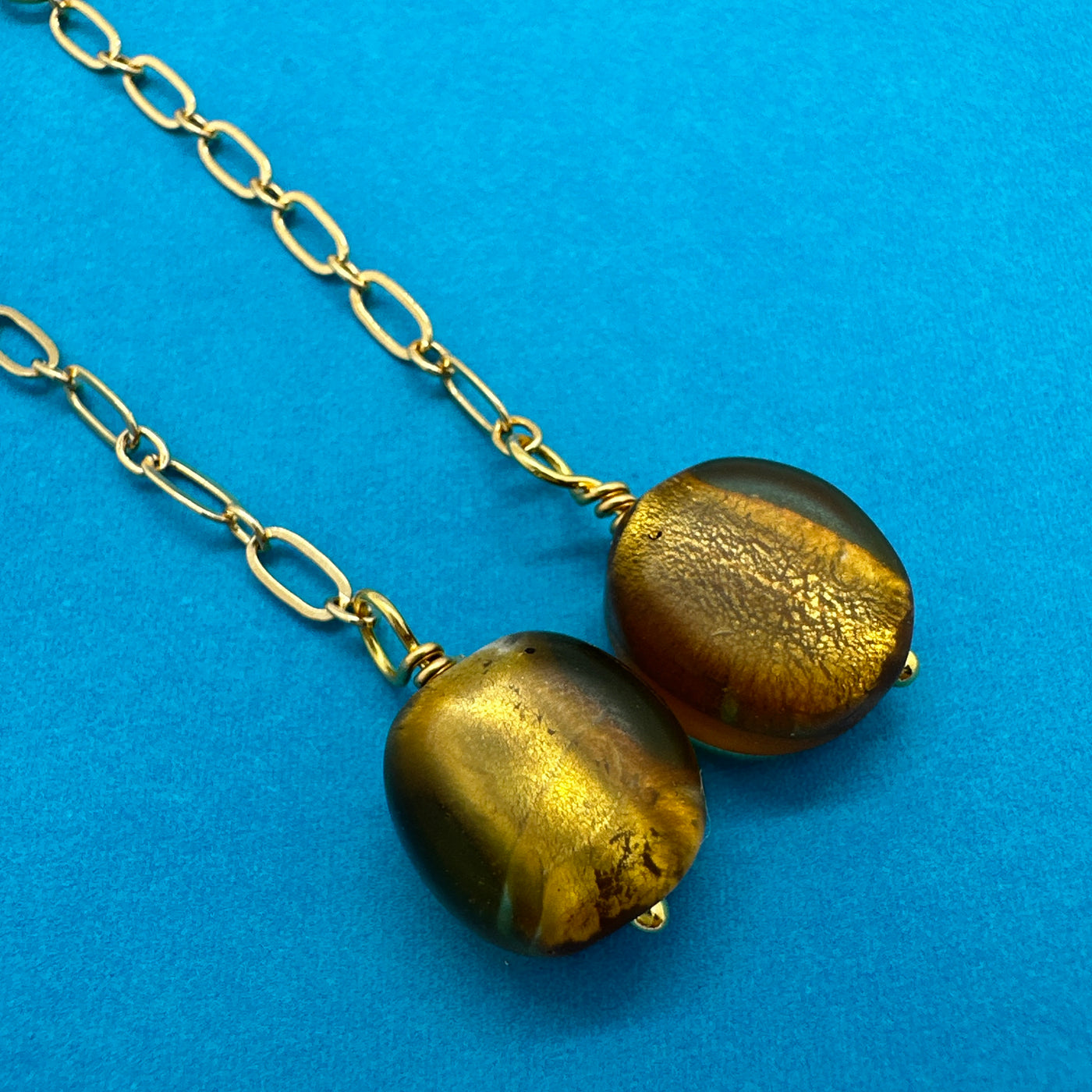 Gold leaf glass pearl attached to brass chain. Earrings are 9 cm long. 6 g