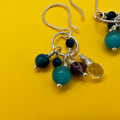 Earrings with blue tiger eye, ocean blue glass and amethyst pearls with a quartz bryolette stemming from a sterling silver circle