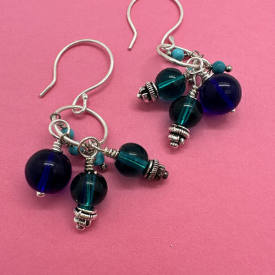 Earrings with cobalt blue crystal, ocean blue glass and turquoise pearls stemming from a sterling silver circle