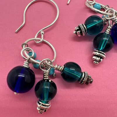 Earrings with cobalt blue crystal, ocean blue glass and turquoise pearls stemming from a sterling silver circle