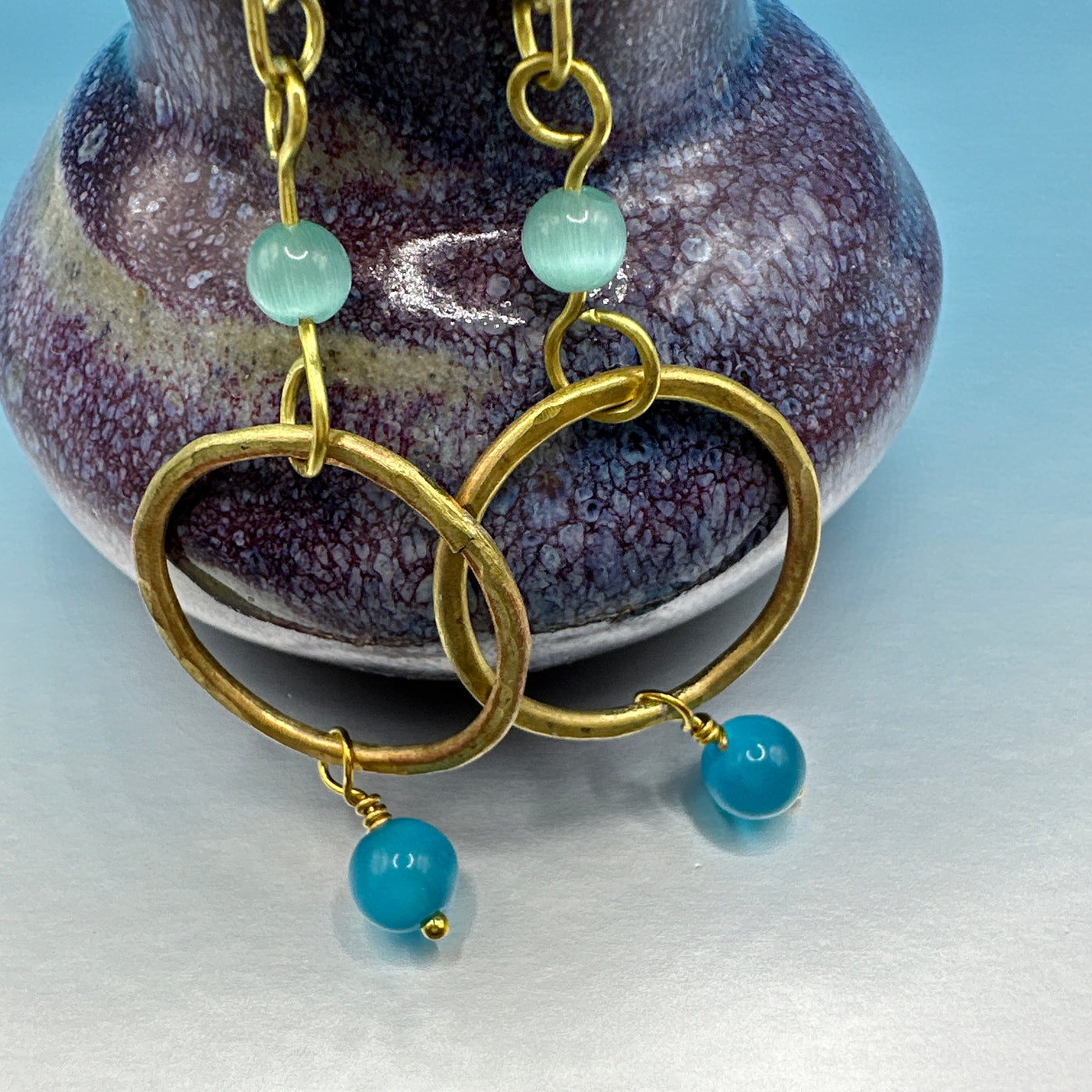 Earrings with dumorterite and celeste blue cats eye and a brass round