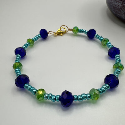 Starres Armband mit blauem und grünem facettiertem Glas und metallisch blauen Perlen