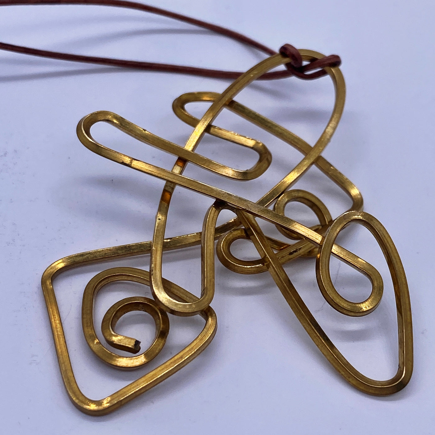 Abstract brass pendant on leather cord (max length 55 cm)