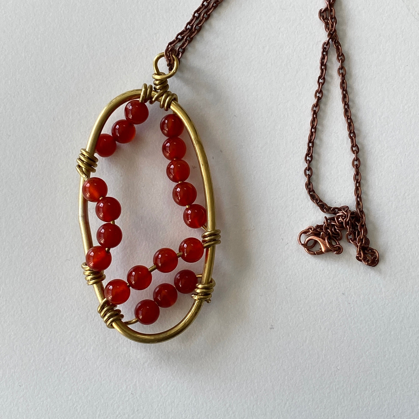 Red agate and copper wire in copper oval pendant