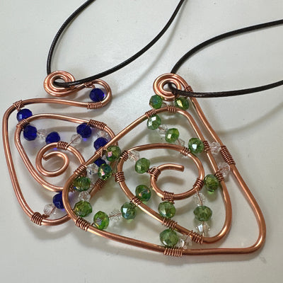 Copper abstract triangle design with green and white chrystals. Leather cord.