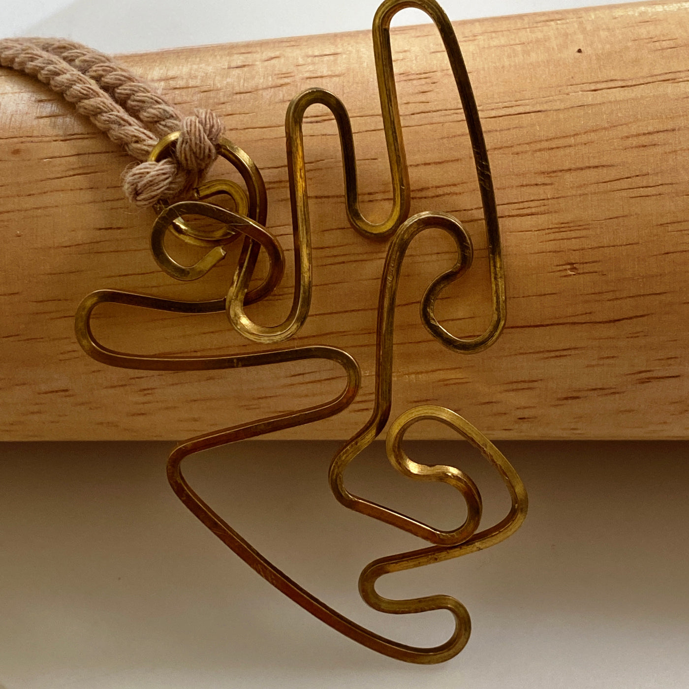 Abstract brass pendant on thick adjustable cord