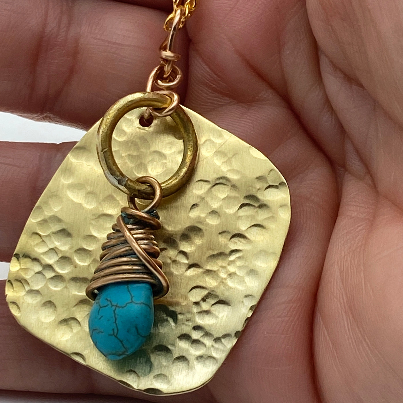 Turquoise pending from a brass circle and square.