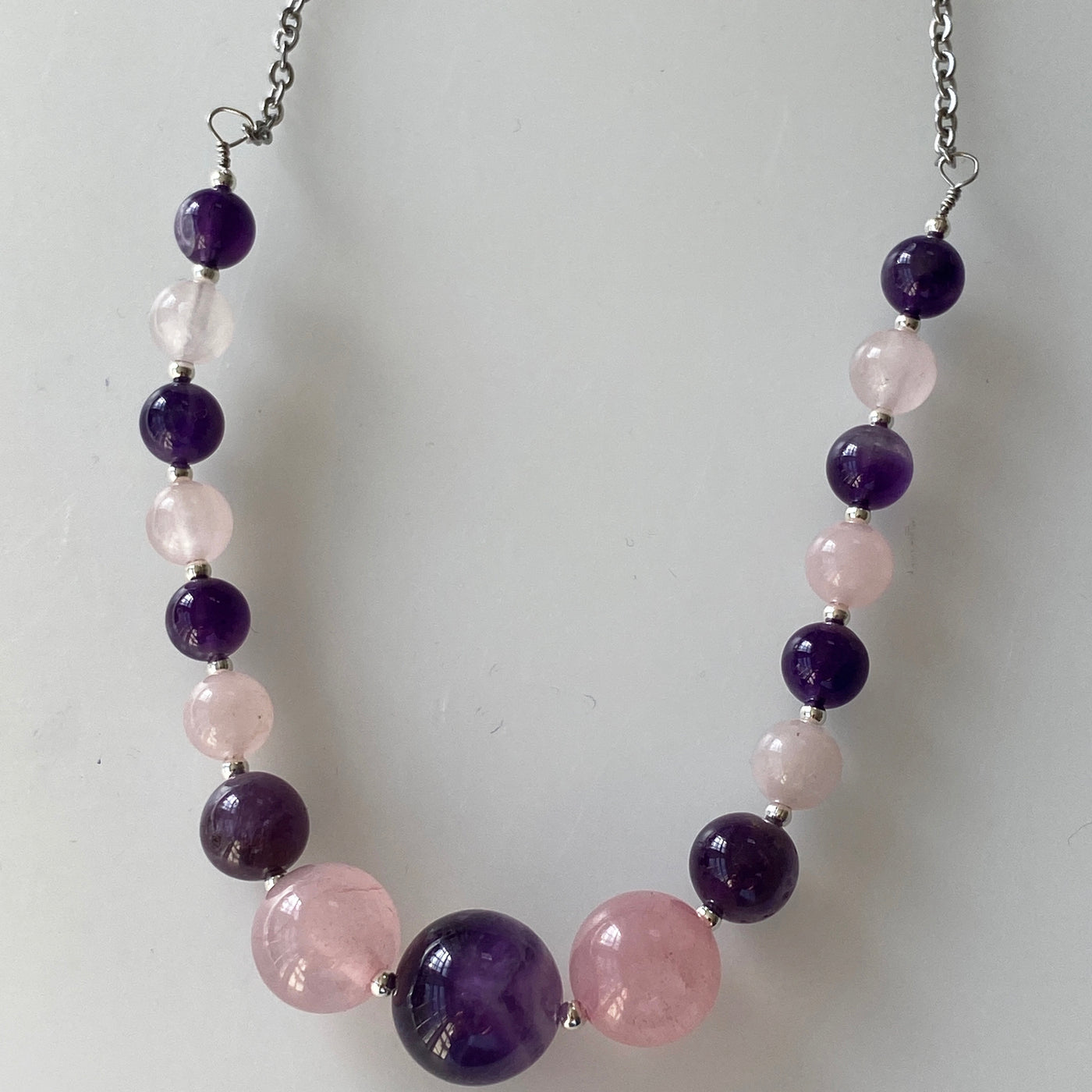 Necklace with growing sizes of rose quartz and amethists