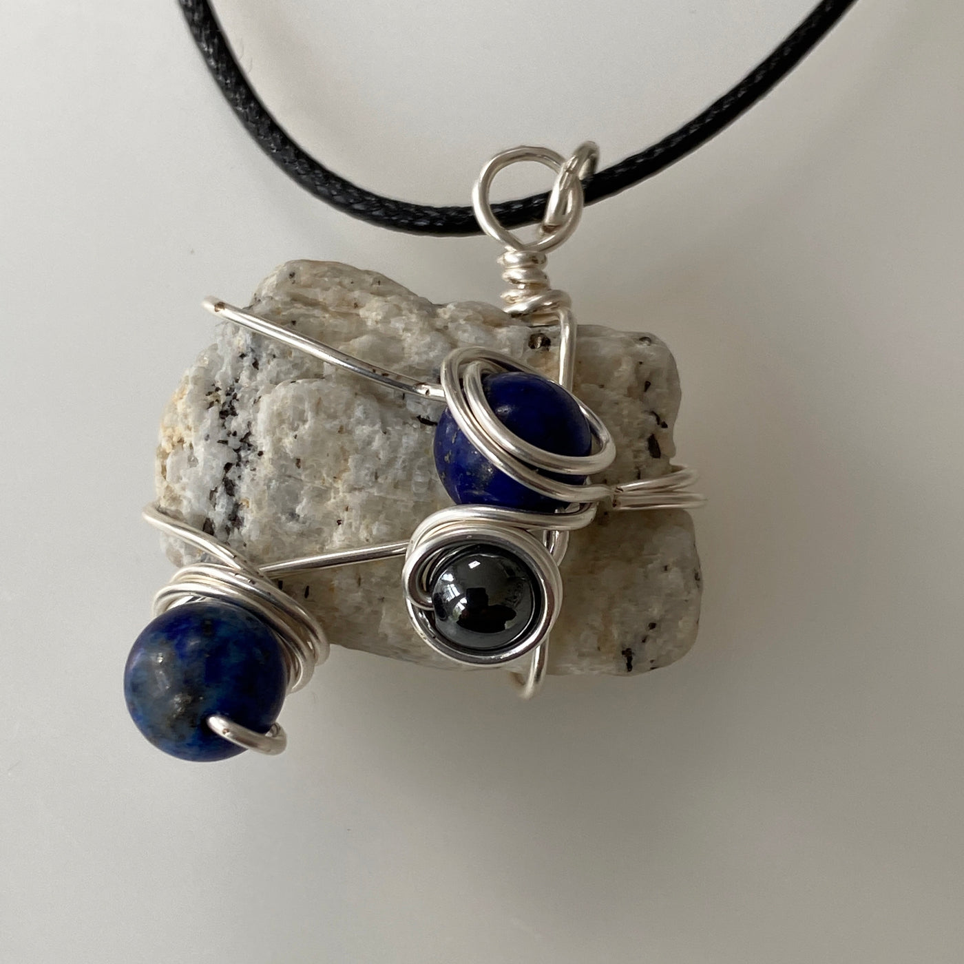 Small pendant featuring white natural stone, lapislazzuli, hematite and silver wire