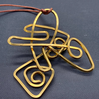 Abstract brass pendant on leather cord (max length 55 cm)
