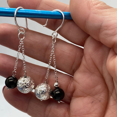 Silberne Lavasteinperlen und tiefschwarze 8-mm-Perlen an einer Kette.