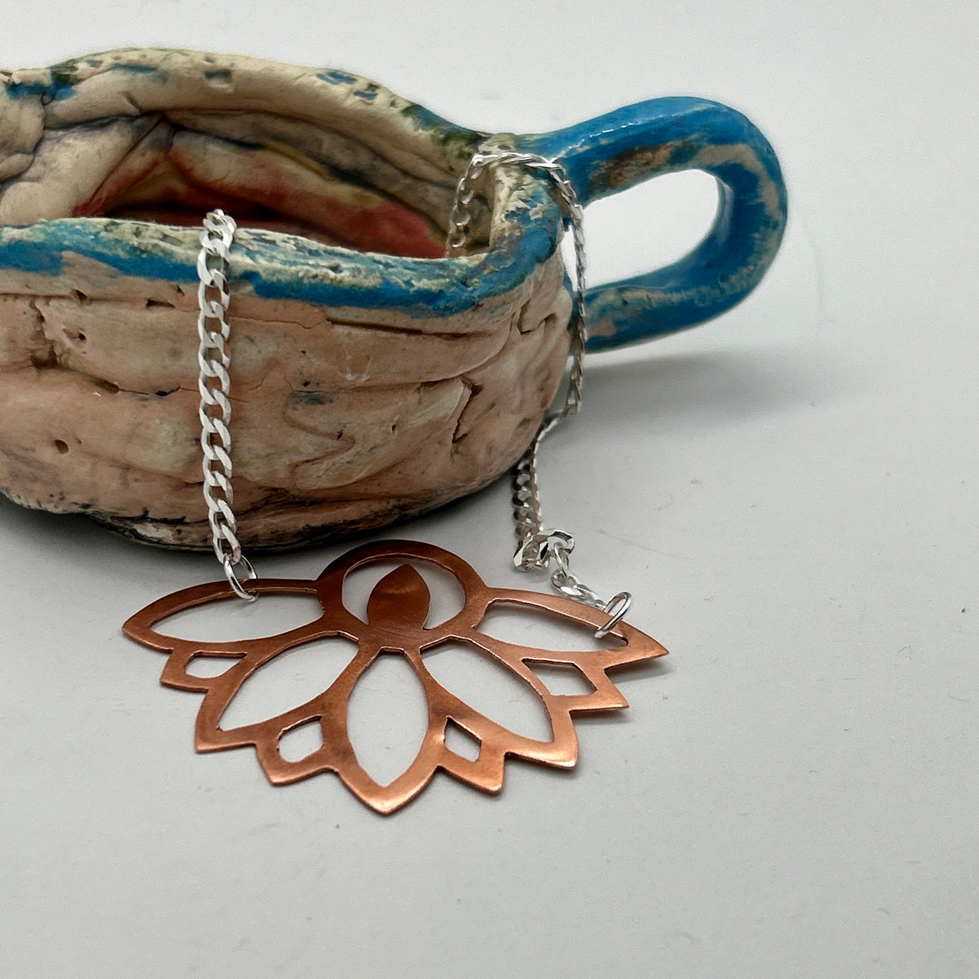 Copper perforated abstract design on silver chain